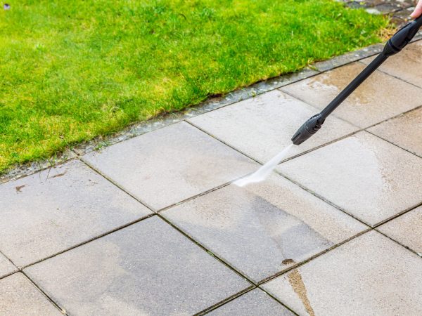 Detail of cleaning terrace with high-pressure water blaster, cleaning dirty paving stones